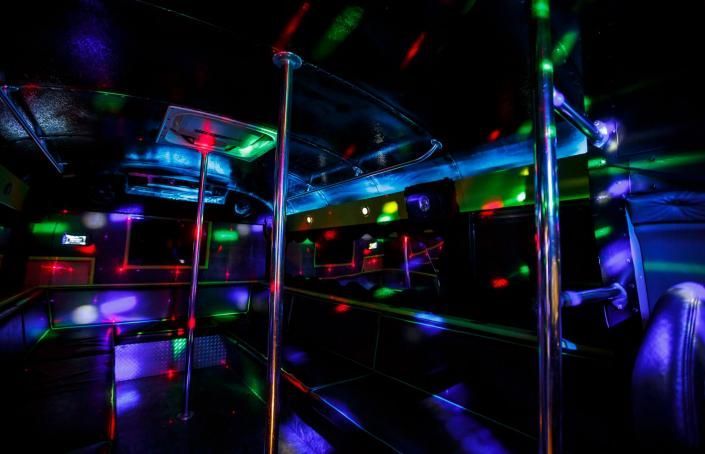 Colorful neon lights reflecting across the interior of an empty bus at night