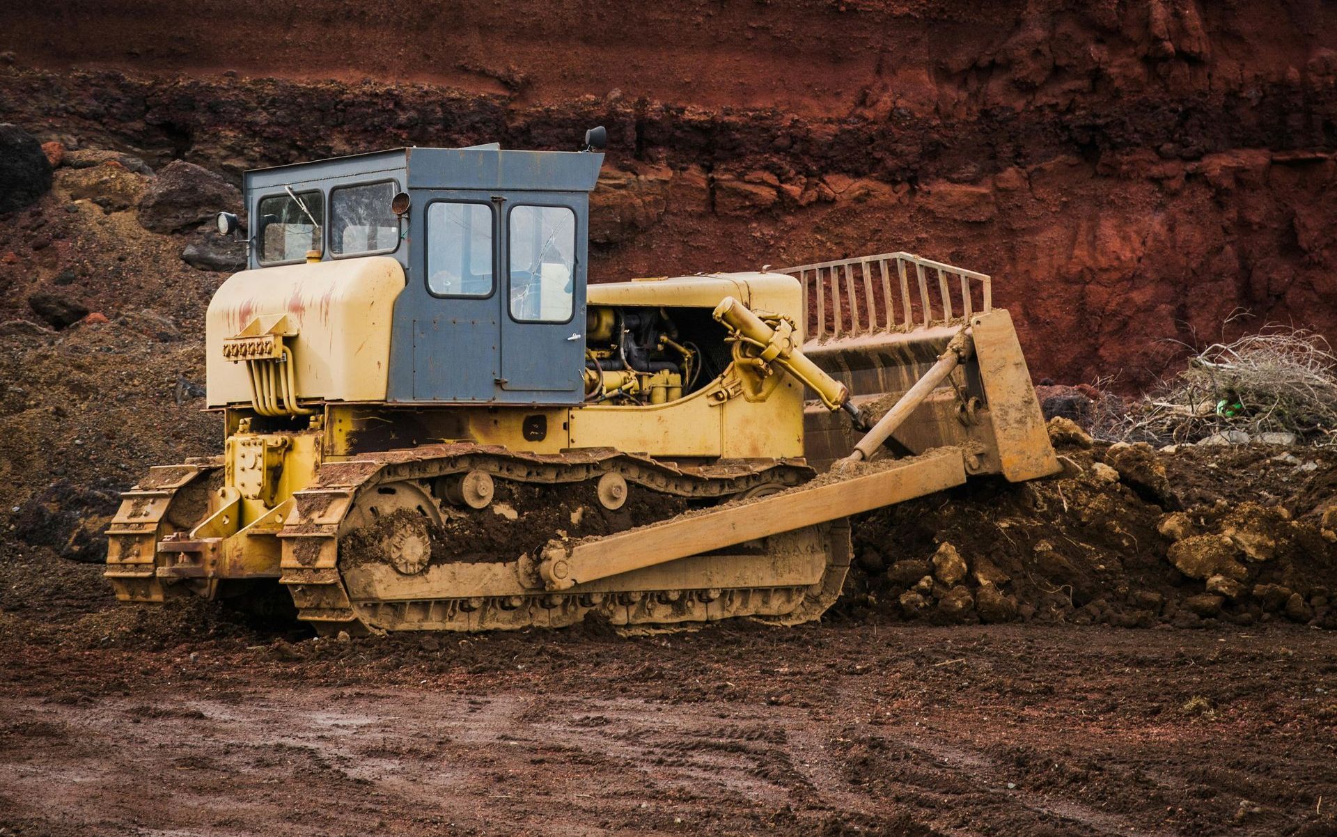 A yellow bulldozer is driving through a dirt field.
