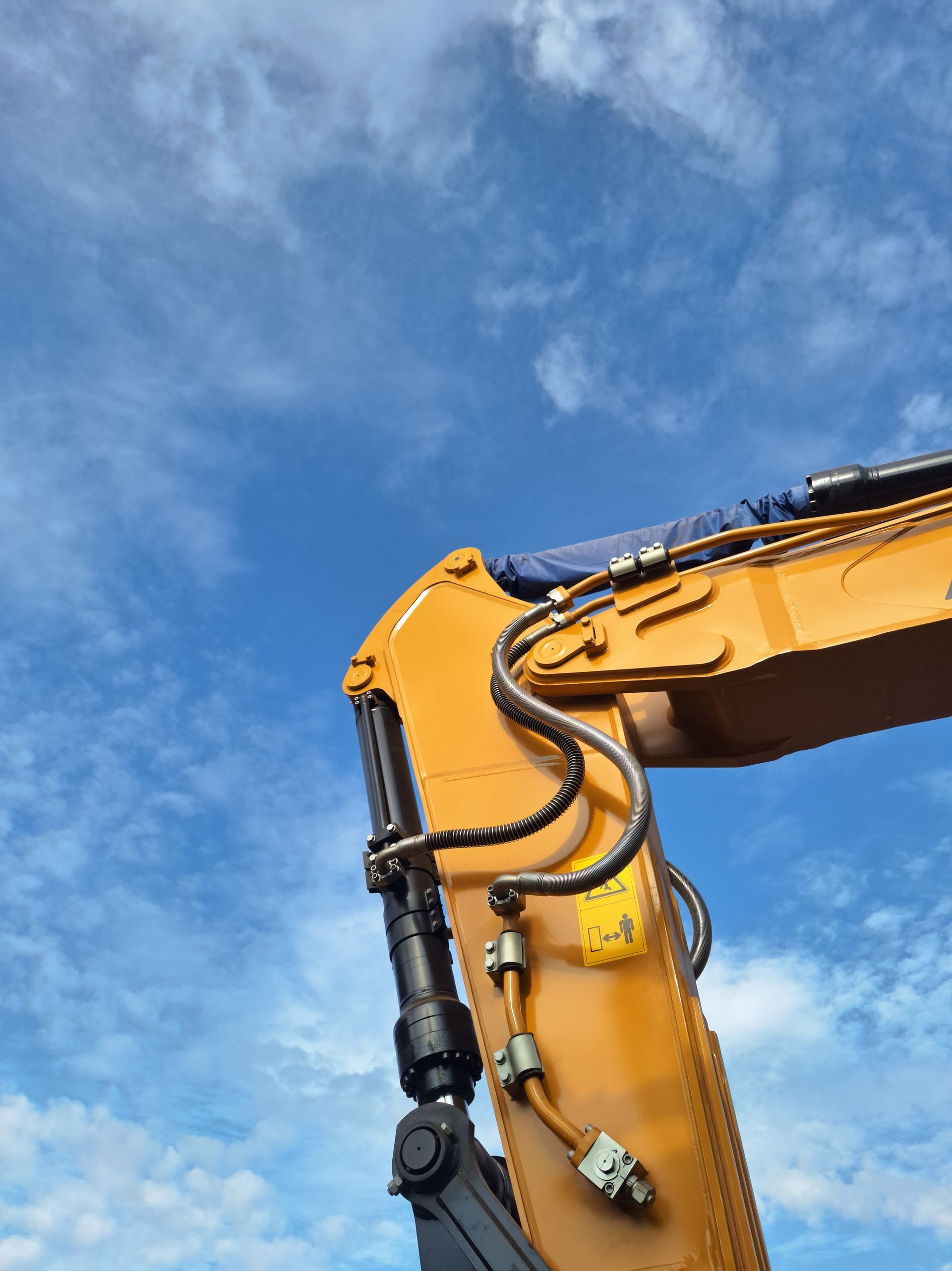 A yellow excavator with a blue sky in the background