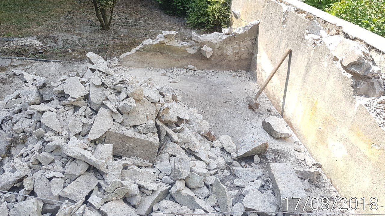 Ein Schutthaufen einer abgerissenen Betonkonstruktion, an deren Wand eine Schaufel lehnt.