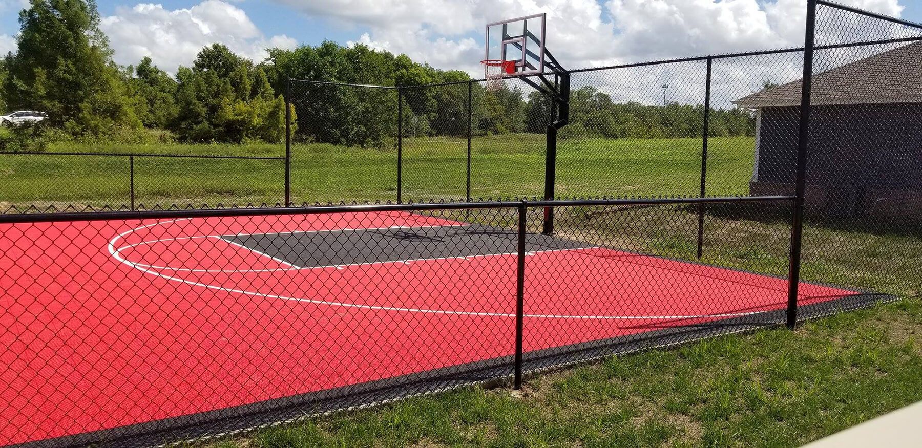 A basketball court with a fence around it and a basketball hoop.