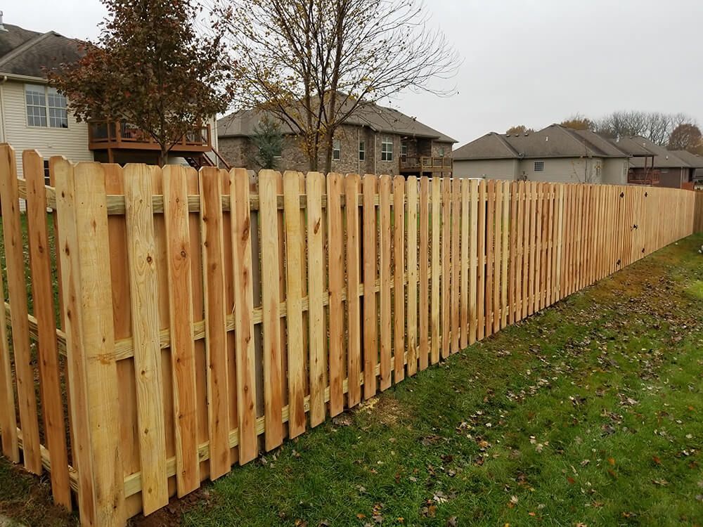 A wooden fence is surrounded by grass and houses in a residential area.