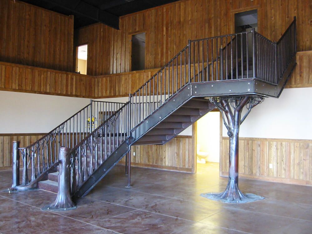 A wooden staircase with a metal railing in an empty room | Fencing showroom springfield mo