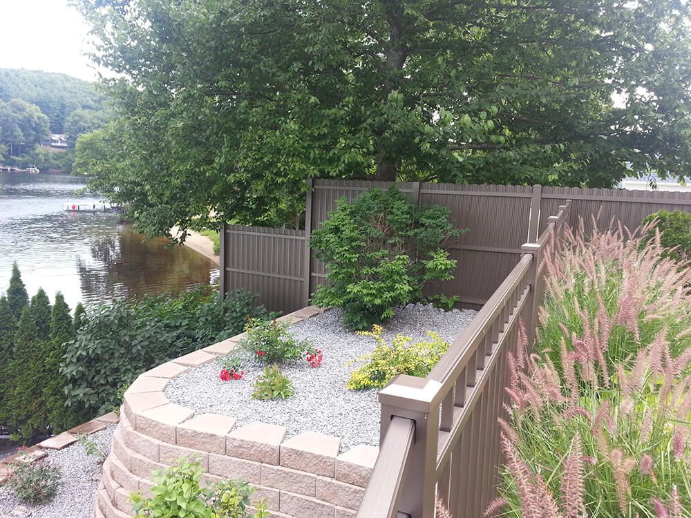 A fence surrounds a garden with a view of a lake.
