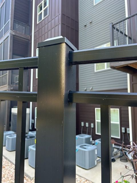 A black fence is in front of a building with air conditioners.