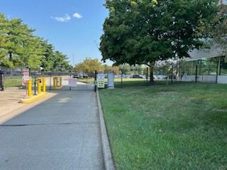 A parking lot with a gate and trees in the background