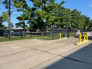 A parking lot with a fence and trees in the background