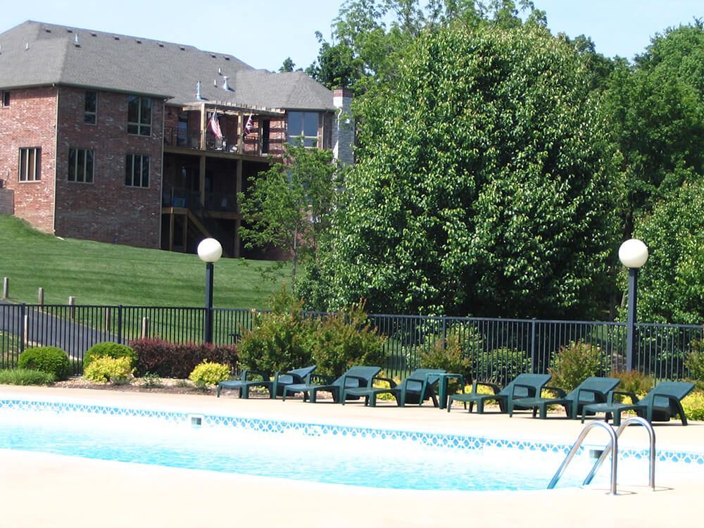 A large brick house is behind a swimming pool