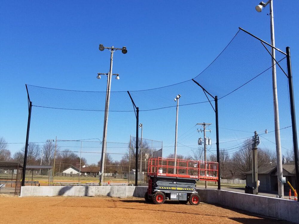 A tractor is parked on a dirt field in front of a fence