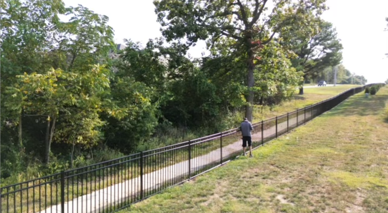 A person is running down a path next to a fence | Commercial fencing company in Springfield and Branson MO