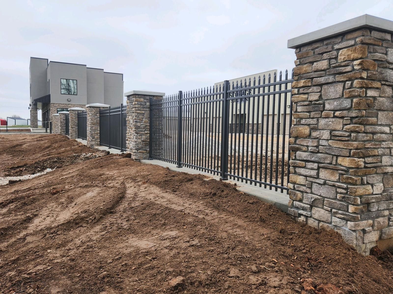 A stone wall with a metal fence surrounding it.