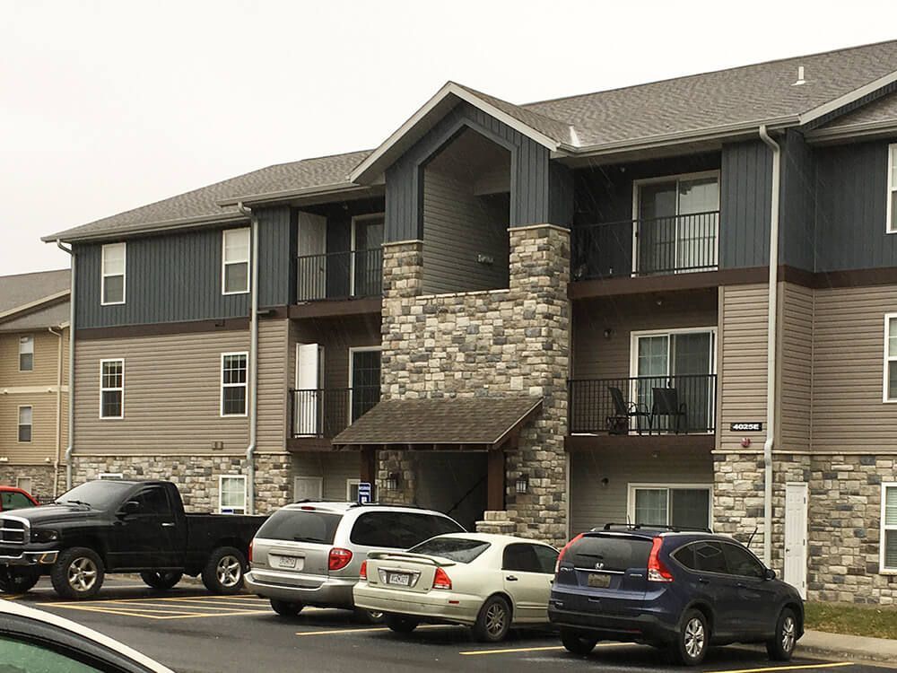 Several cars are parked in front of a large apartment building