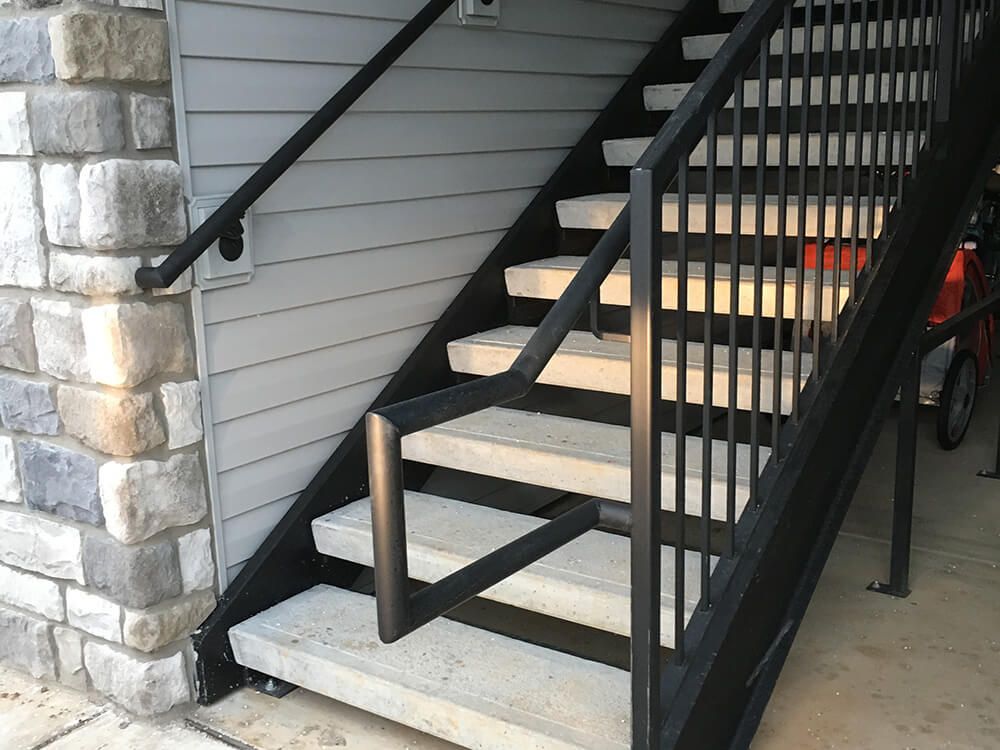 A set of stairs leading up to a building with a black railing.