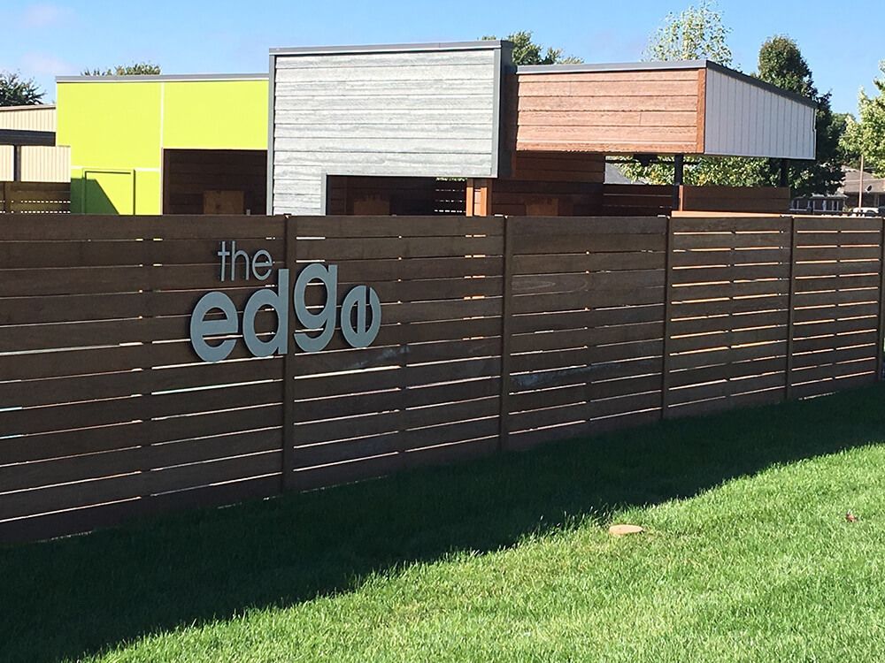 A wooden fence with the words the edge written on it