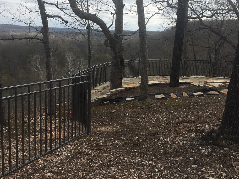 There is a fence in the middle of the woods with a view of the mountains.