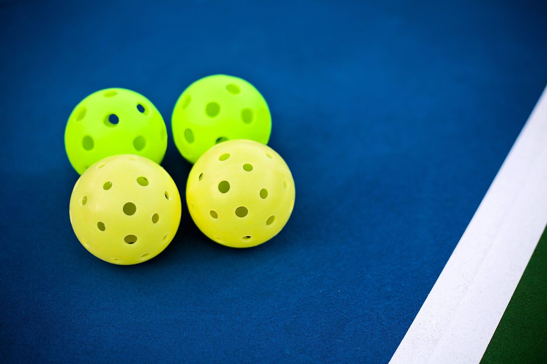 Three yellow balls are sitting on top of a blue tennis court.