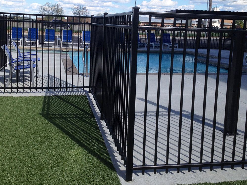 A black metal fence surrounds a swimming pool