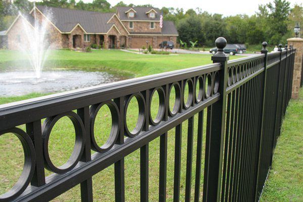 A black fence surrounds a large house with a fountain in the background | Fence by Springfield MO fencing contractor