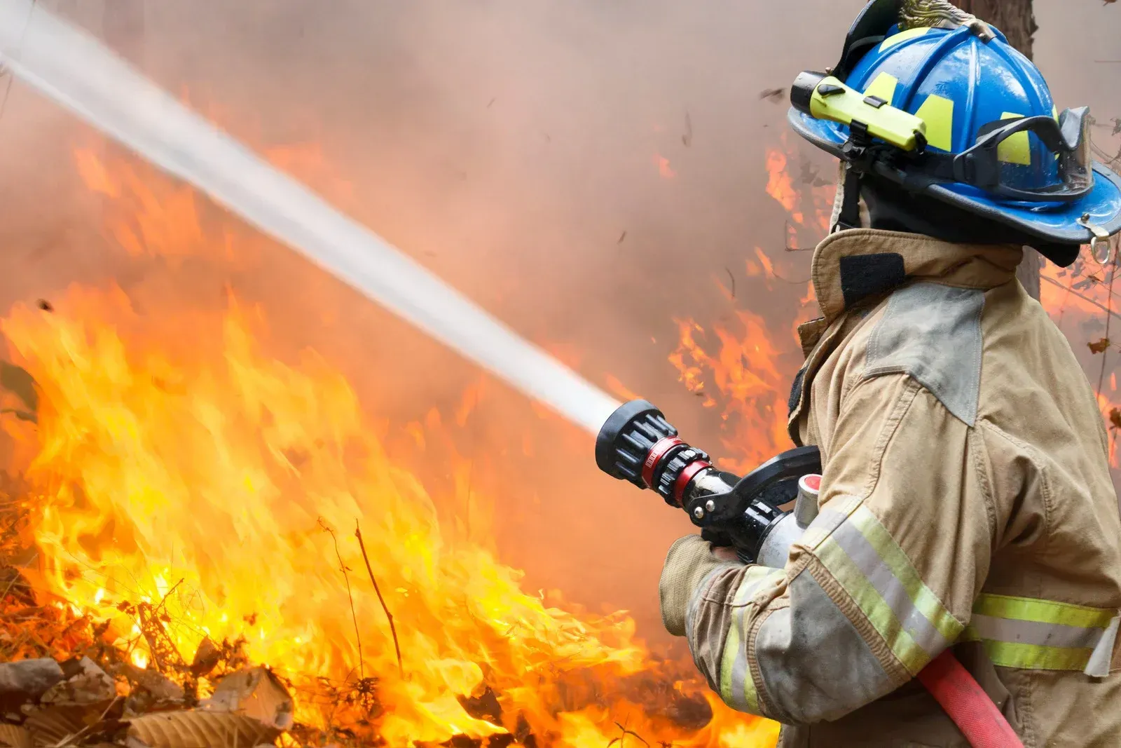 A fireman is spraying water on a fire with a hose.