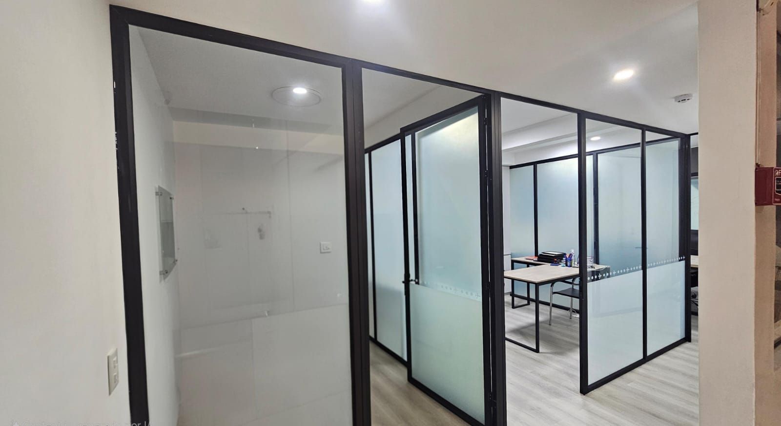 Espacio de oficina con paredes divisorias de vidrio y vidrio esmerilado.