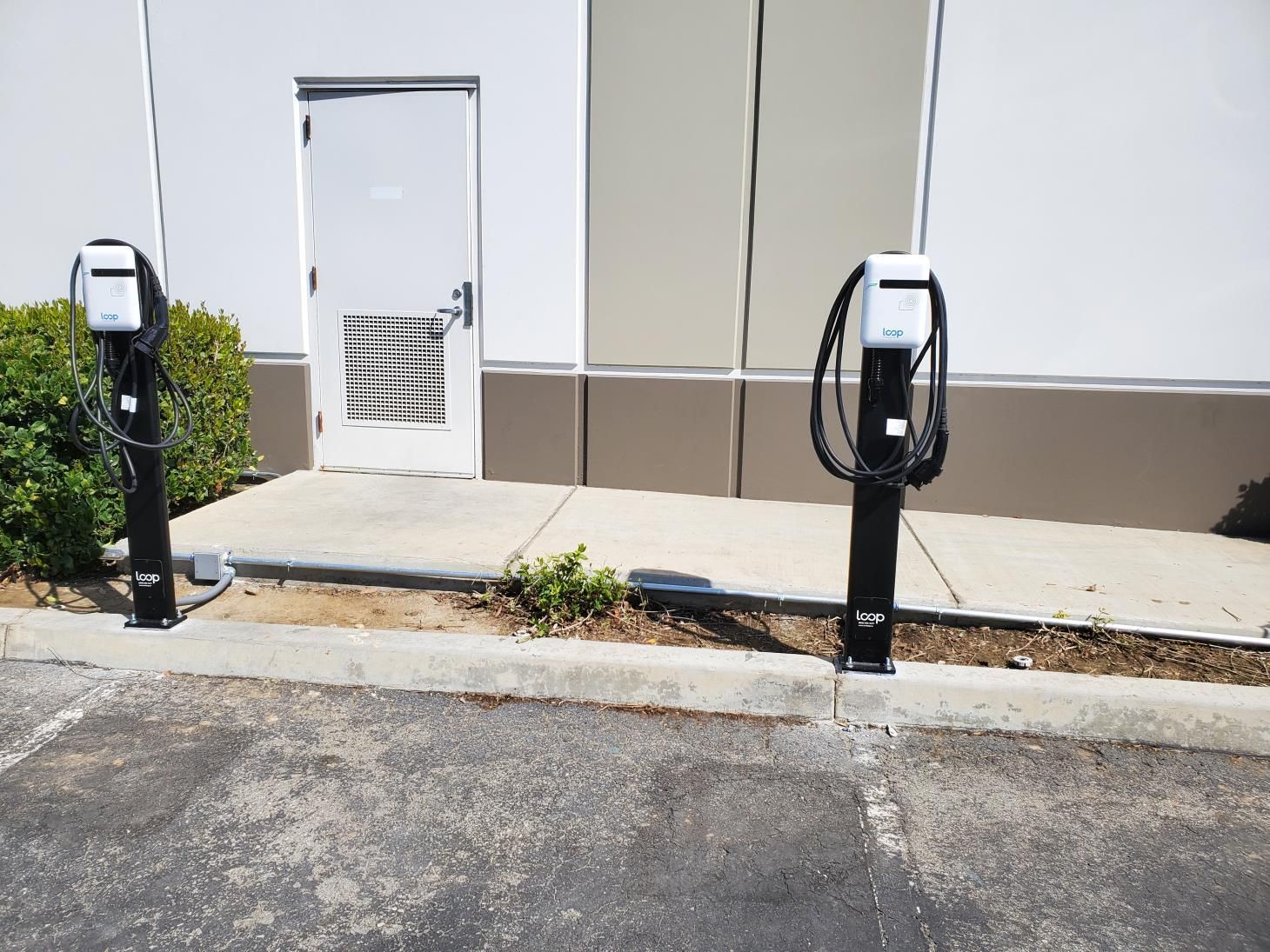 Two electric vehicle charging stations in front of a building