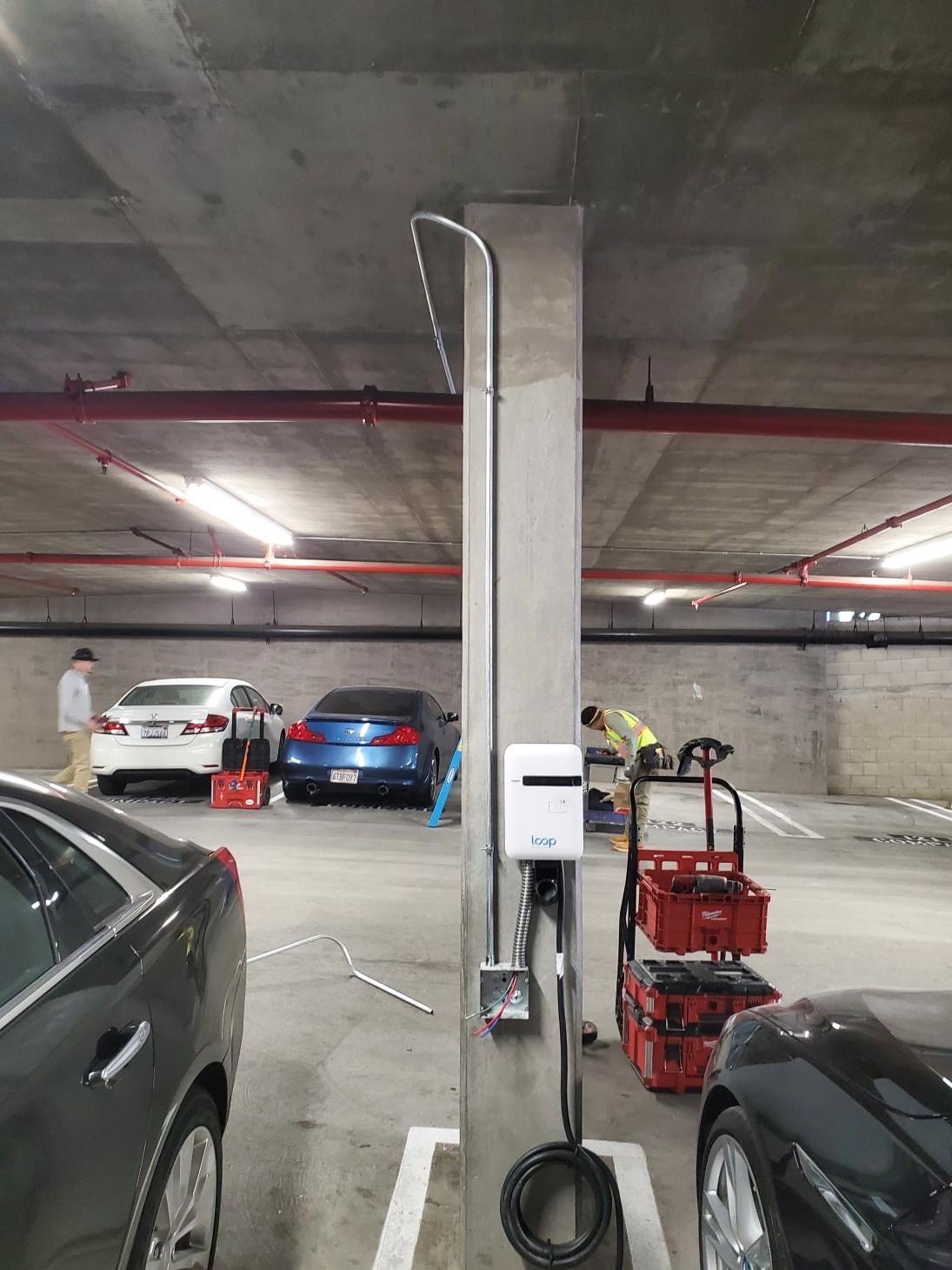 A parking garage with cars parked in it and a pillar in the middle.