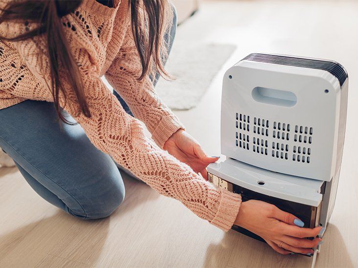 A woman changing the water container of a modern dehumidifier