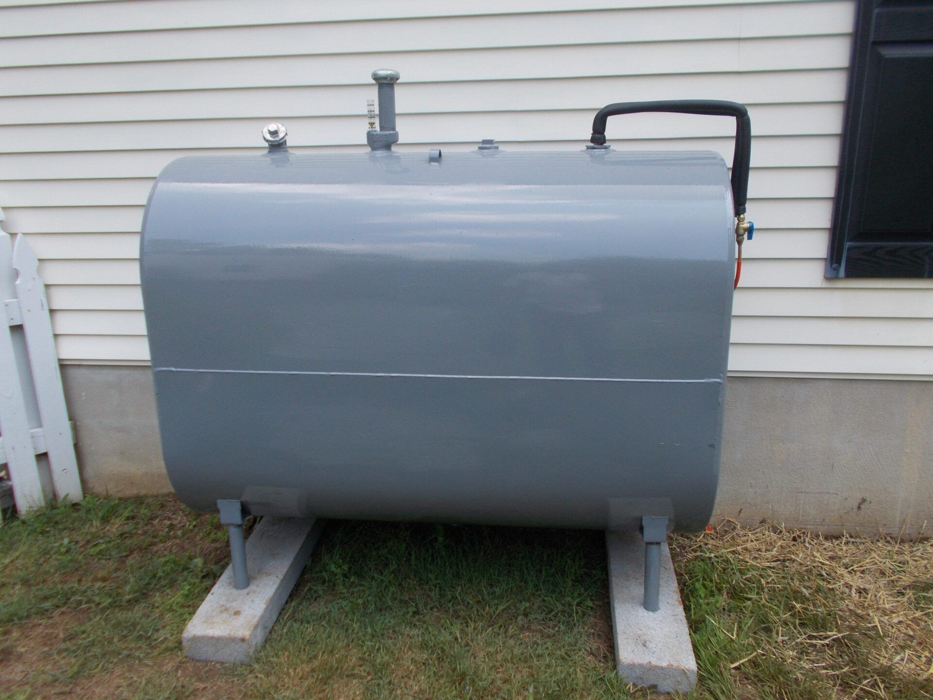 A large heating fuel oil tank positioned next to an exterior wall, providing energy for heating purposes.