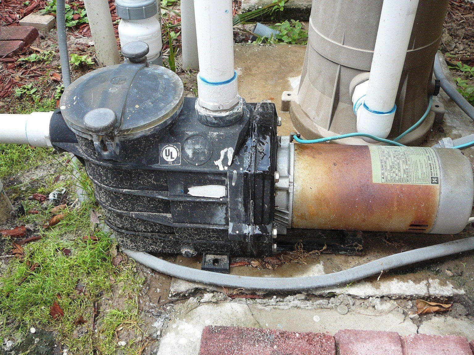 An aging pool pump with a weathered exterior, showing signs of rust and wear.