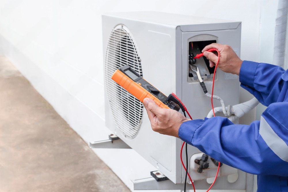 a man is fixing an air conditioner with a multimeter .