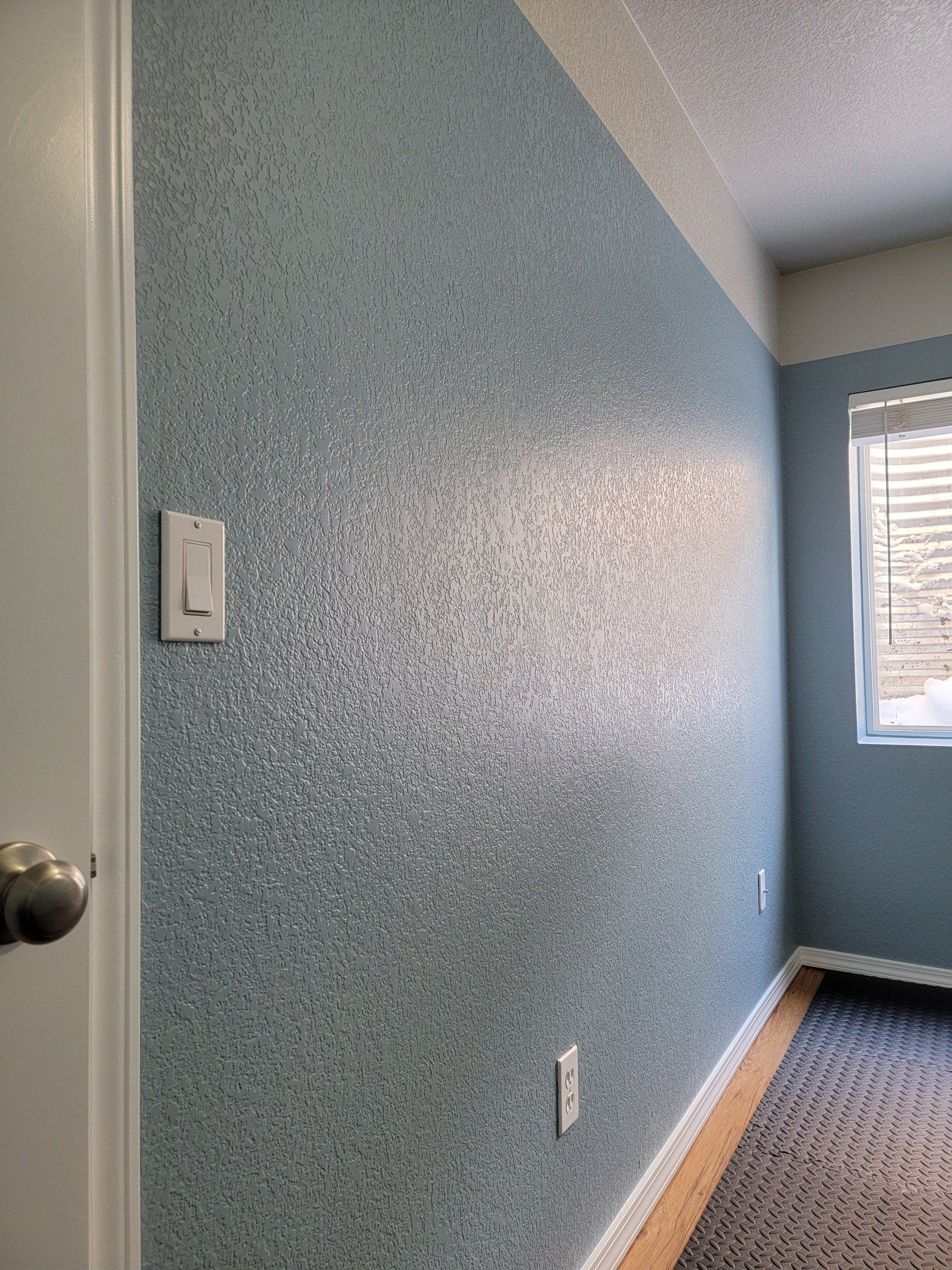 A hallway with a light switch on the wall and a window.