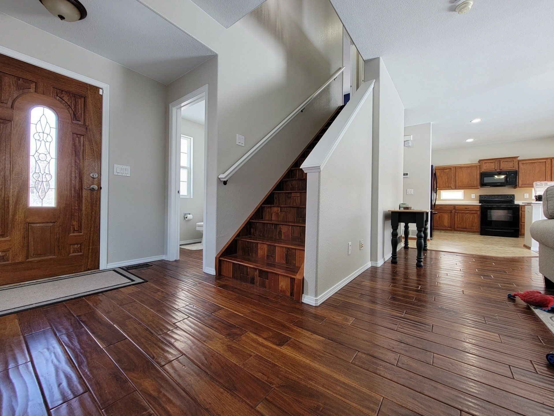 A living room with hardwood floors and stairs leading up to the second floor.