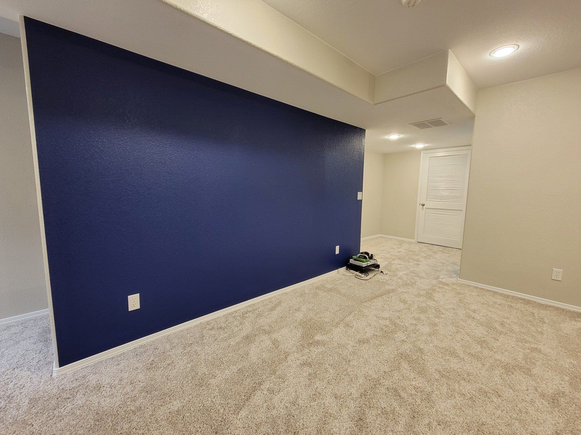 An empty room with a blue wall and a carpeted floor.