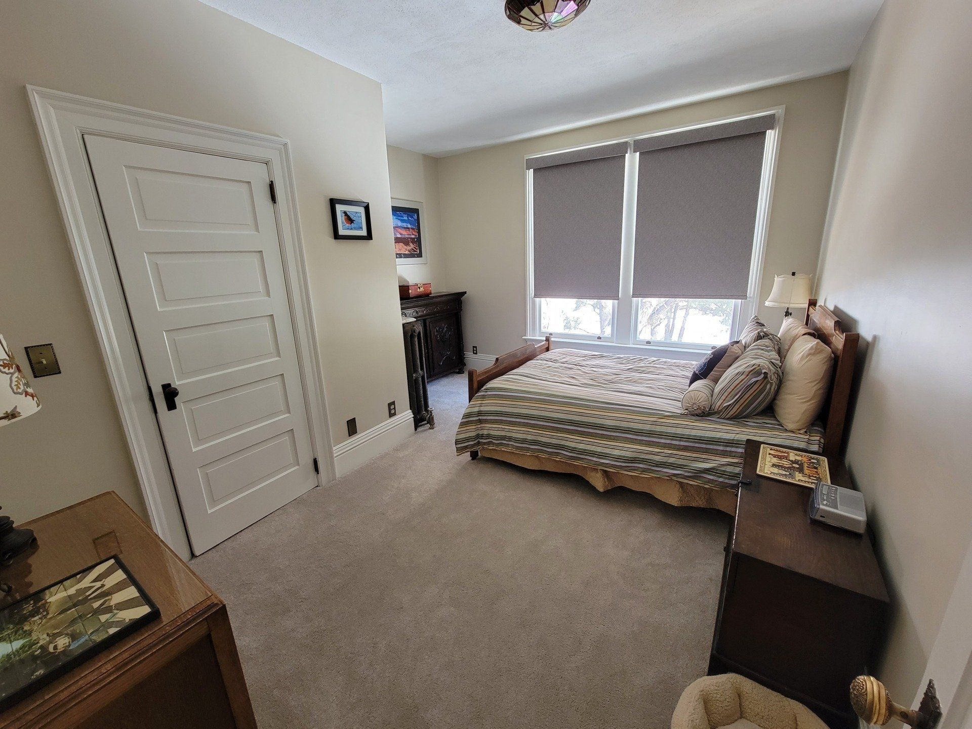 A bedroom with a bed , nightstand , and two windows.