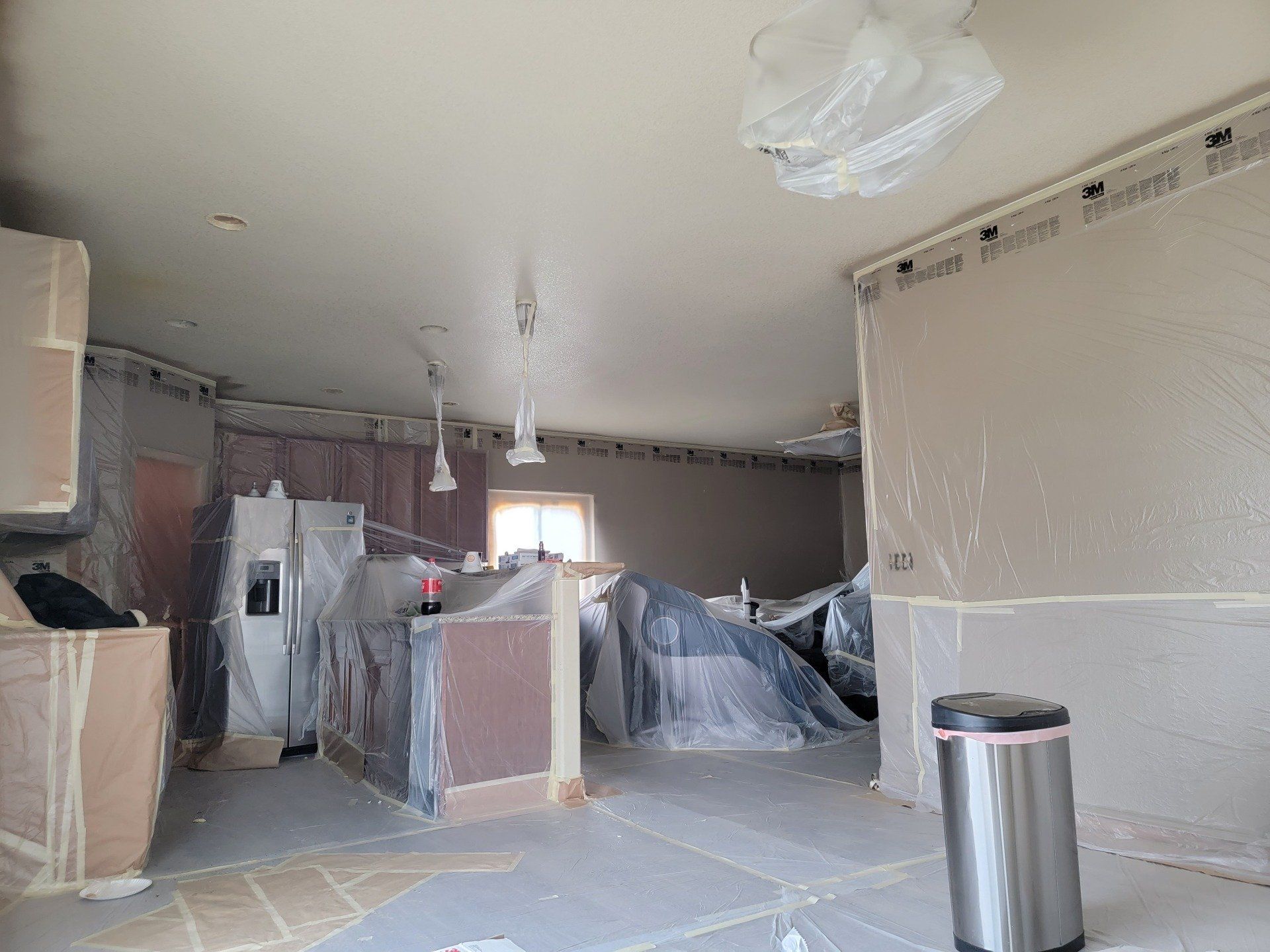 A room with a trash can in it is being painted.