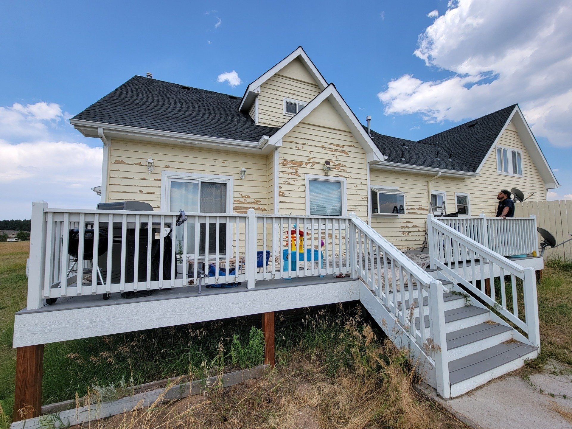 The back of a house with a large deck and stairs leading up to it.