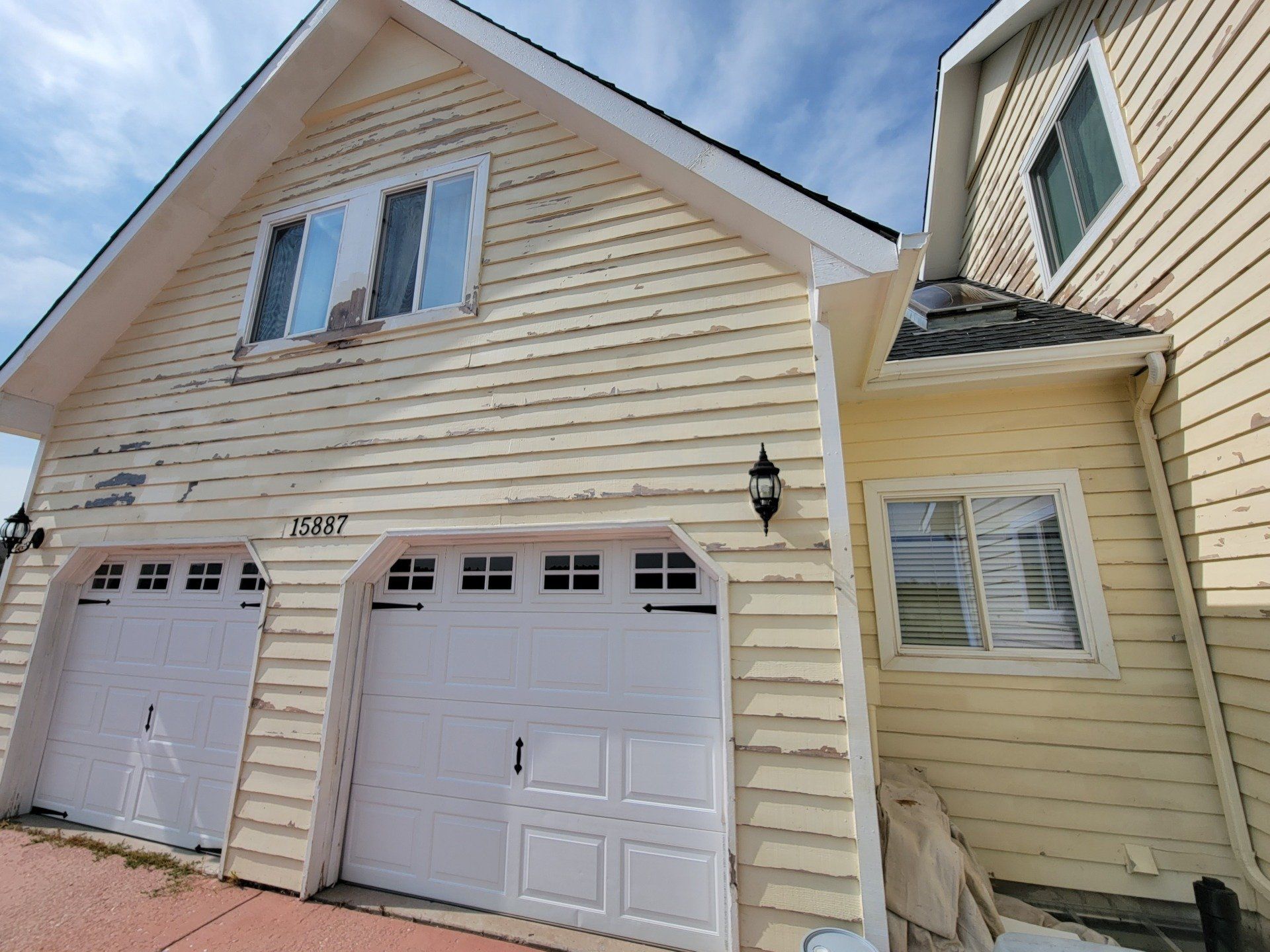 A yellow house with a white garage door and windows.