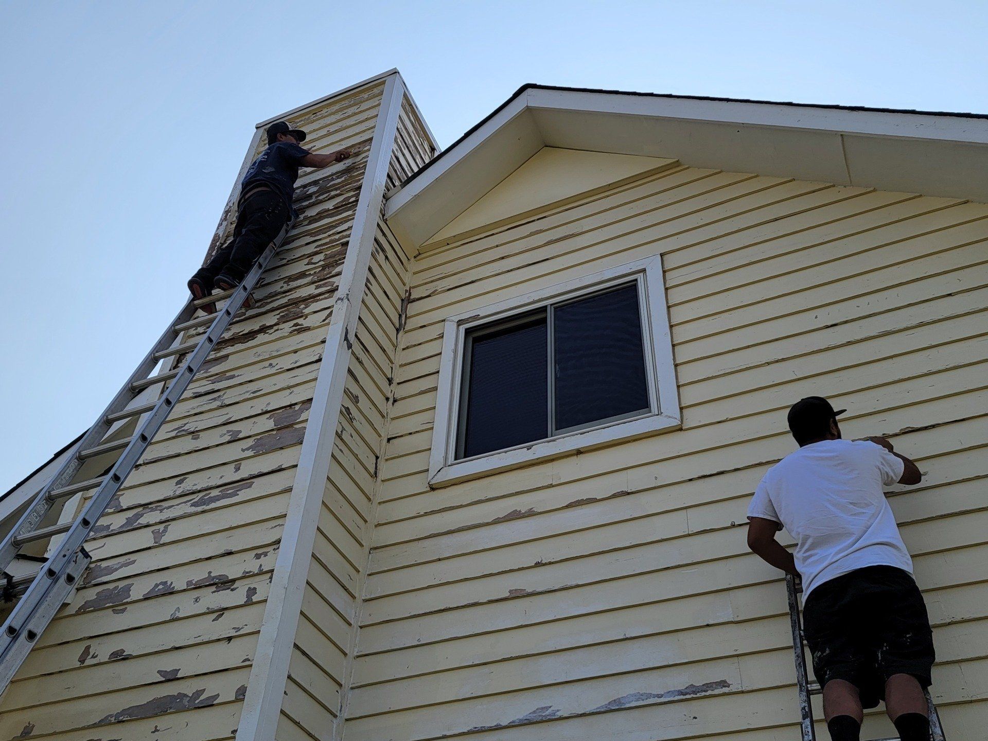 Professional Painters scraping peeling paint off the exterior of a house in Colorado Springs