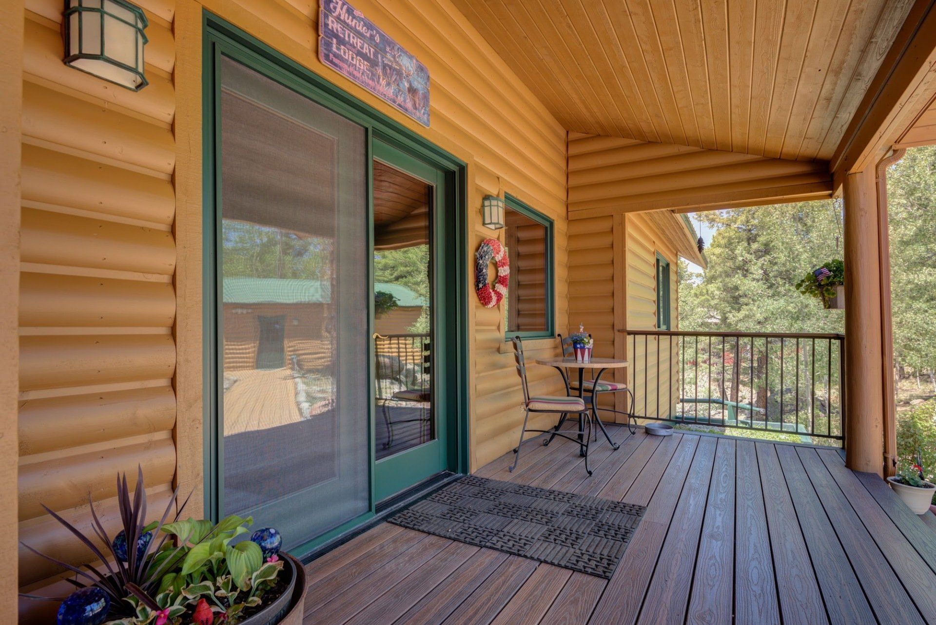 A wooden deck with a table and chairs on it in a log cabin.