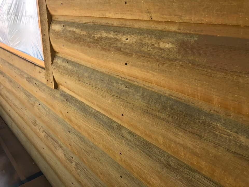 A close up of a log cabin wall with a window.