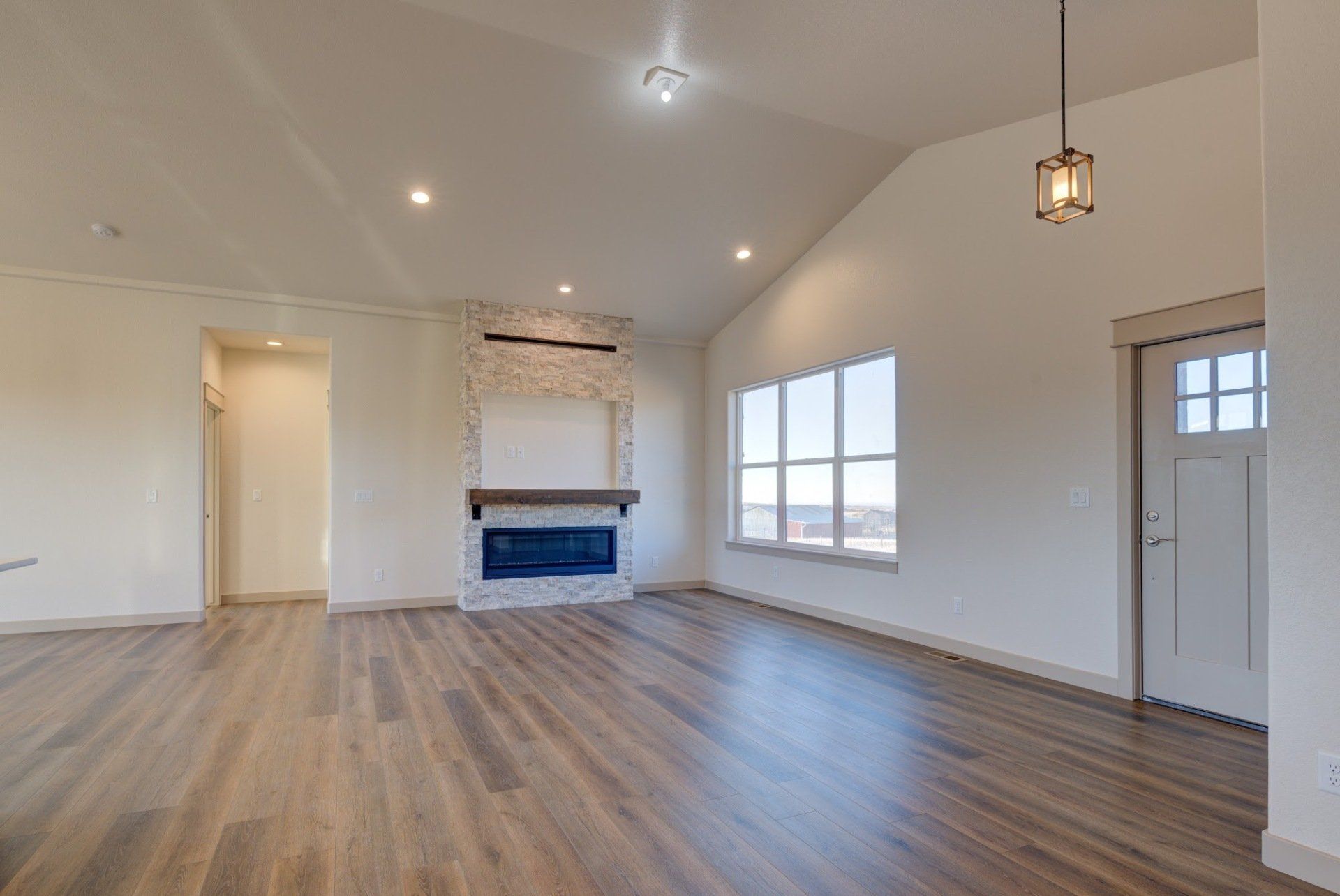 An empty living room with hardwood floors and a fireplace.