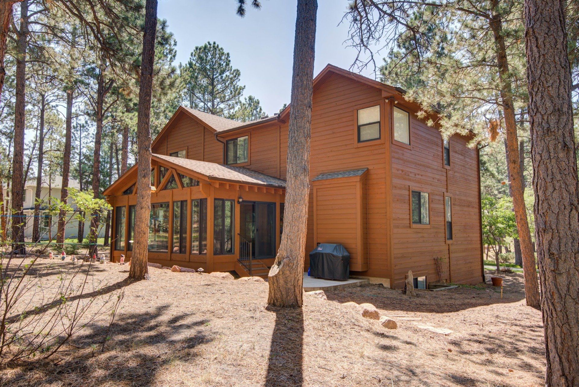 A large wooden house is surrounded by trees in the woods.