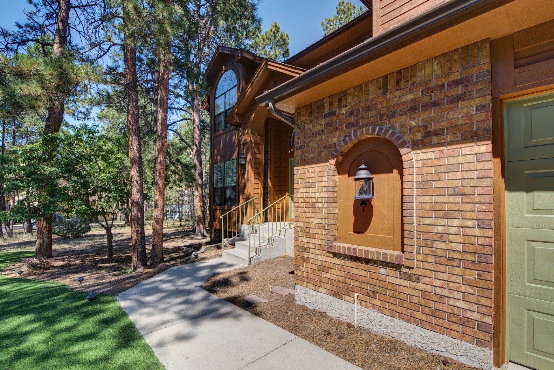 A brick house with a green door and a walkway leading to it.