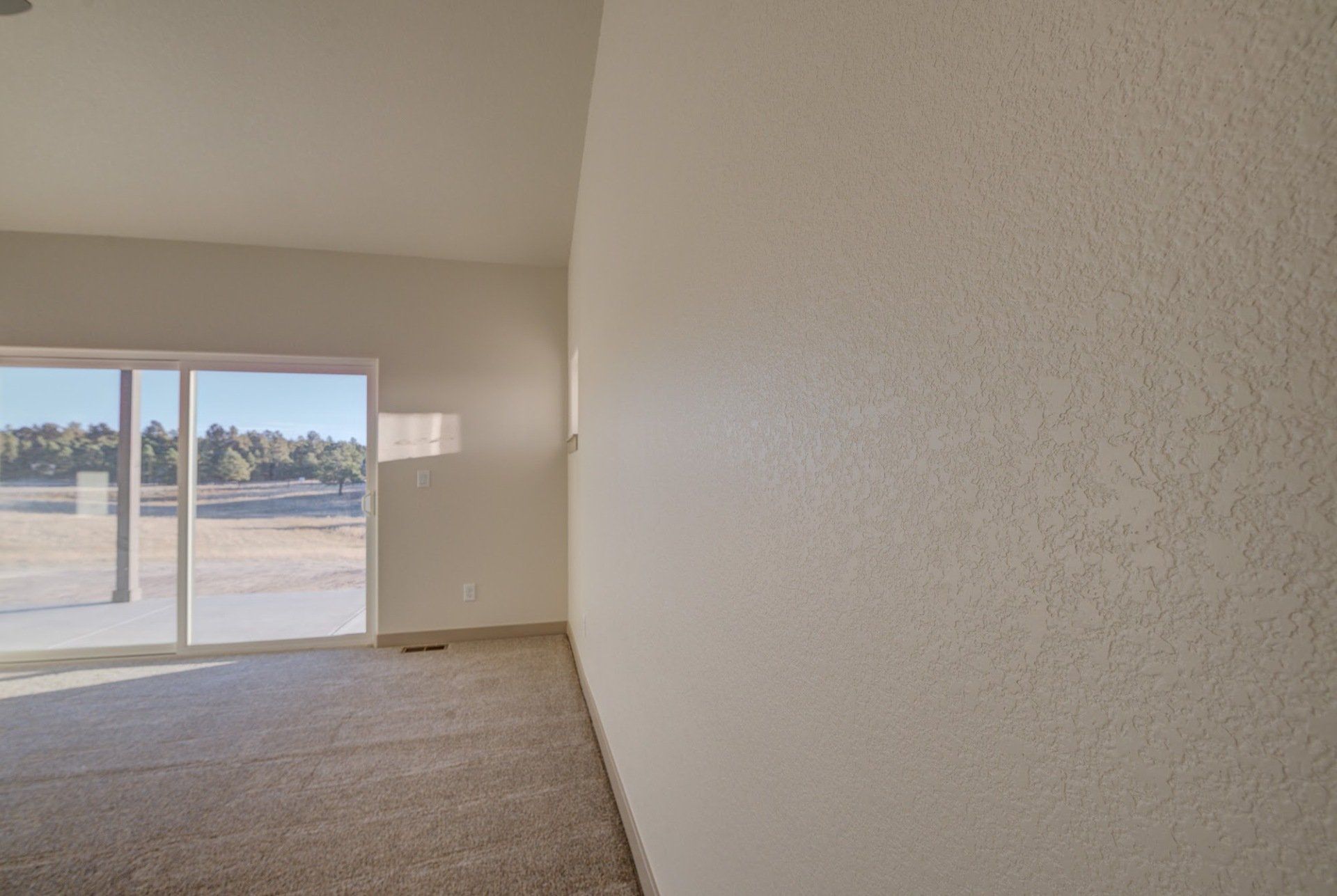 an empty room with a sliding glass door and a white wall .