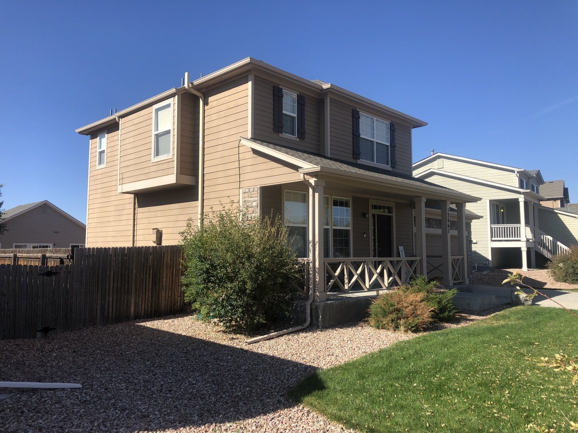A house with a porch and a fence in front of it.