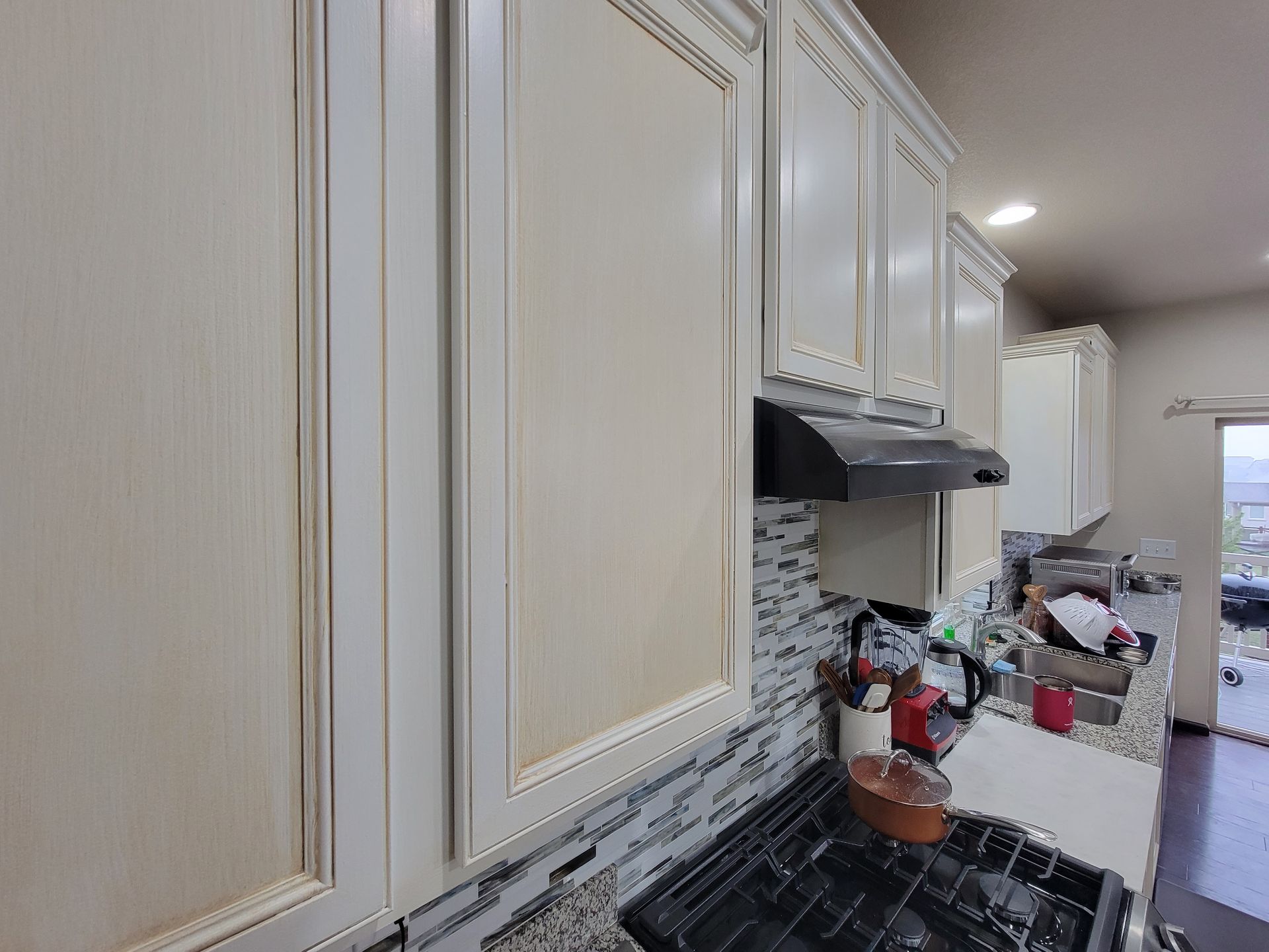 A kitchen with white cabinets and a black stove top oven.