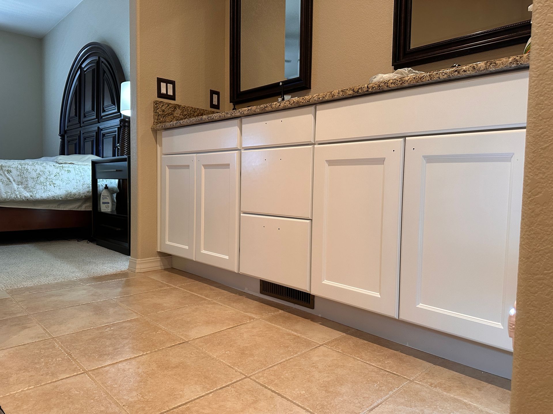 Cabinet Refinishing: A bathroom with white cabinets , granite counter tops , and two mirrors.