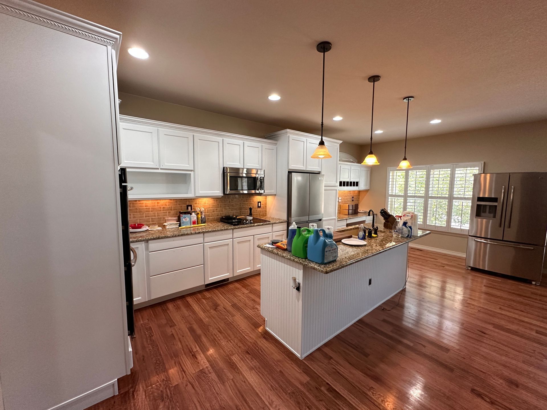 Cabinet Refinishing: A kitchen with white cabinets and stainless steel appliances.