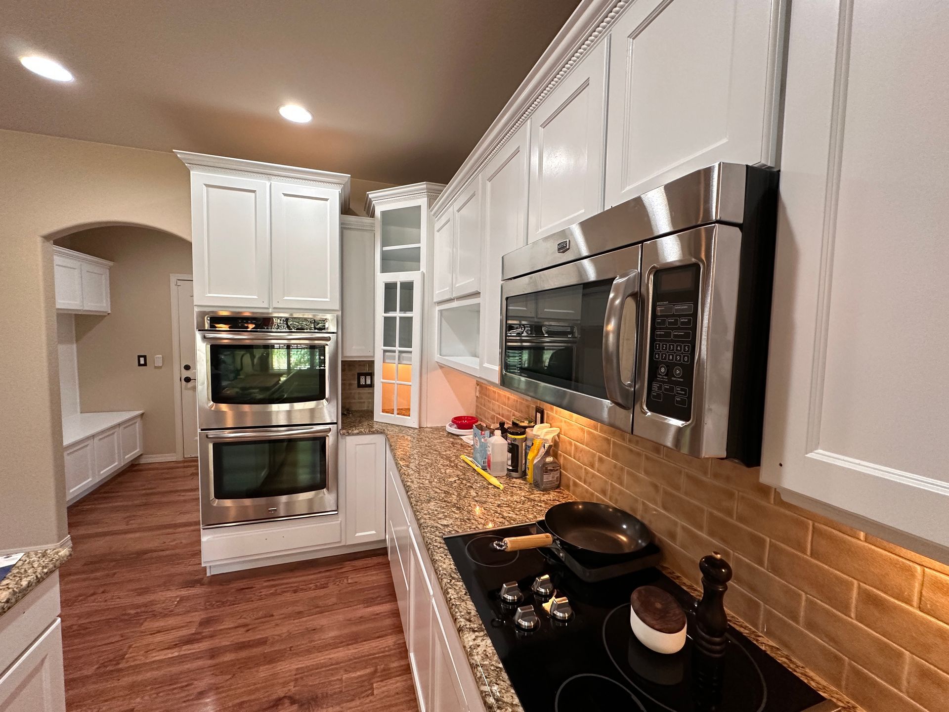 Cabinet Refinishing: A kitchen with white cabinets and stainless steel appliances.