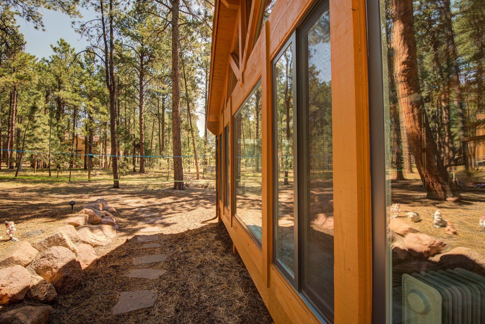 A wooden house with a lot of windows in the woods.